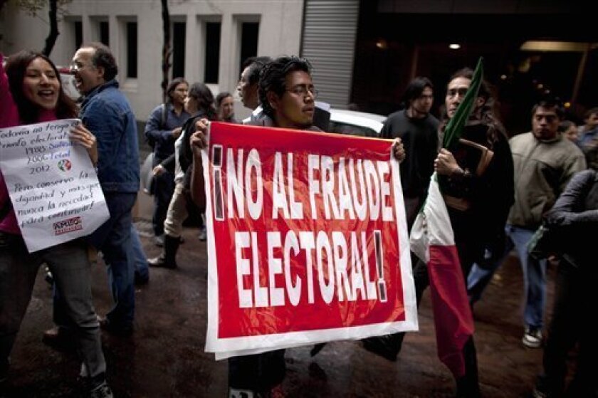 A man holds up a sign that reads in Spanish "No to electoral fraud" outside a hotel where Mexican presidential candidate Andres Manuel Lopez Obrador of the Democratic Revolution Party (PRD), gave a news conference in Mexico City, Monday, July 2, 2012. After official results showed Enrique Pena Nieto of the Institutional Revolutionary Party (PRI) winning 38 per cent of the vote with more than 92 per cent of the votes counted, Lopez Obrador has not conceded Sunday’s elections, telling his supporters Monday evening that, “We can’t accept a fraudulent result,” a reference to his allegations that Pena Nieto exceeded campaign spending limits, bought votes in some states and benefited from favorable coverage in Mexico’s semi-monopolized television industry. (AP Photo/Alexandre Meneghini)