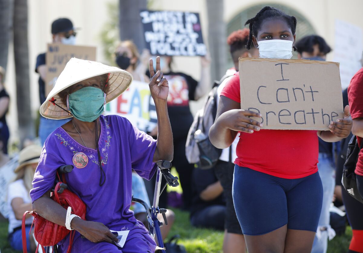 Linda Miles, left, and her great niece Aaniyah Hooker, 9, attend a protest outside Escondido City Hall 