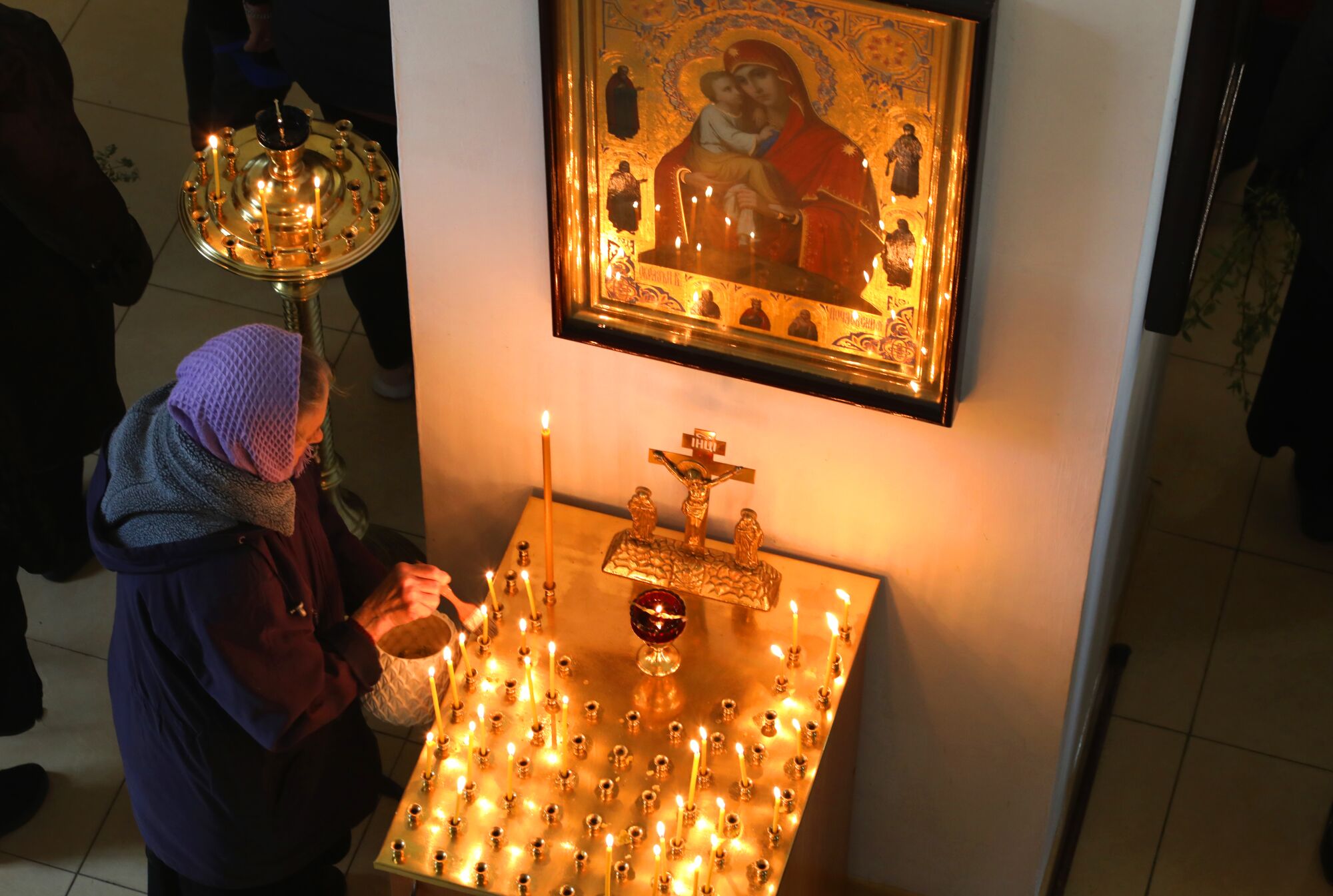 A woman lights a candle inside a church.