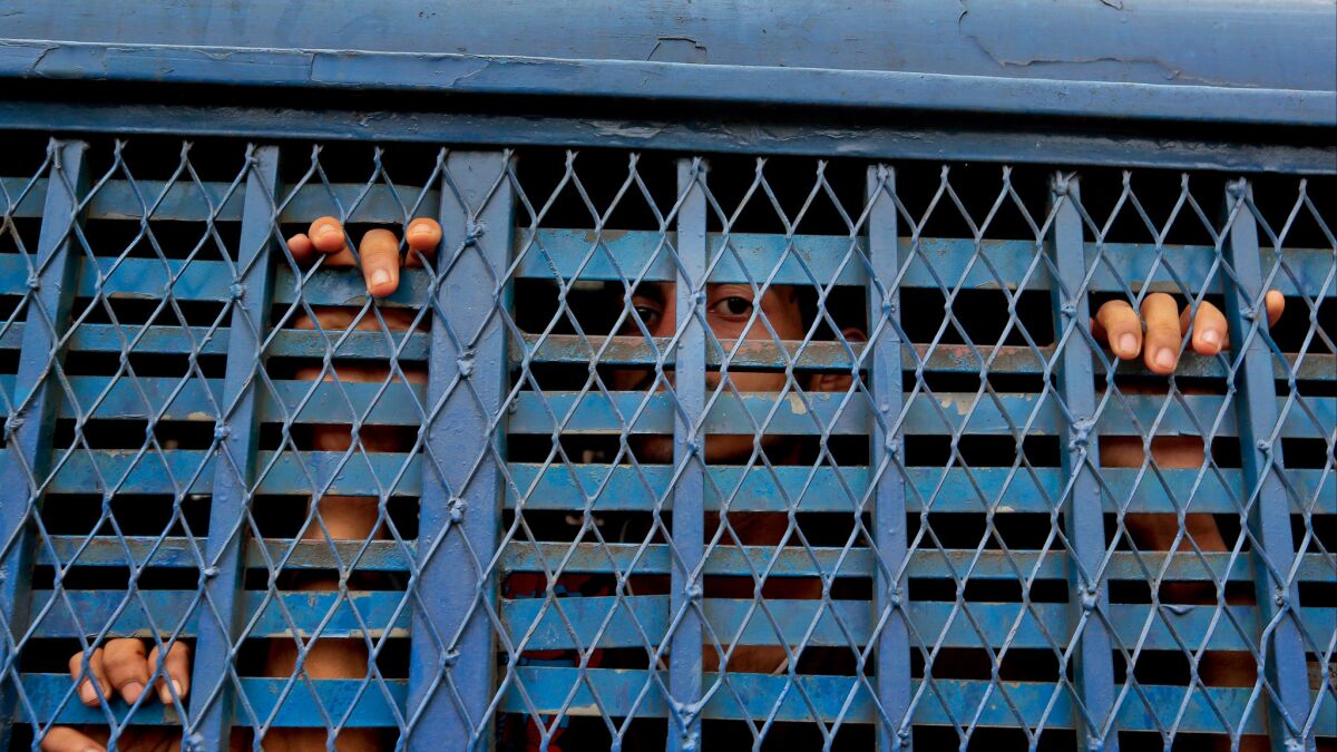 Bangladeshi men detained as part of crackdown on extremists look out from a prison van outside a court building in Dhaka on Monday.
