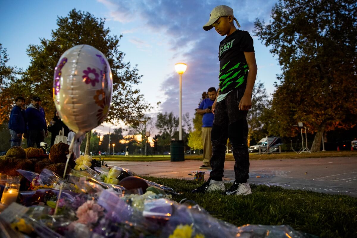 Sebastian Martinez, 12, a friend of Saugus High School shooting victim Dominic Blackwell, places a football with Dominic’s jersey number written on it at a memorial at Central Park on Friday in Santa Clarita.