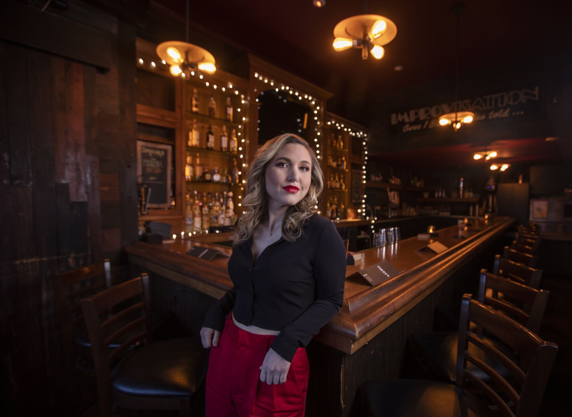 Comedian Taylor Tomlinson leans against a bar at the Hollywood Improv
