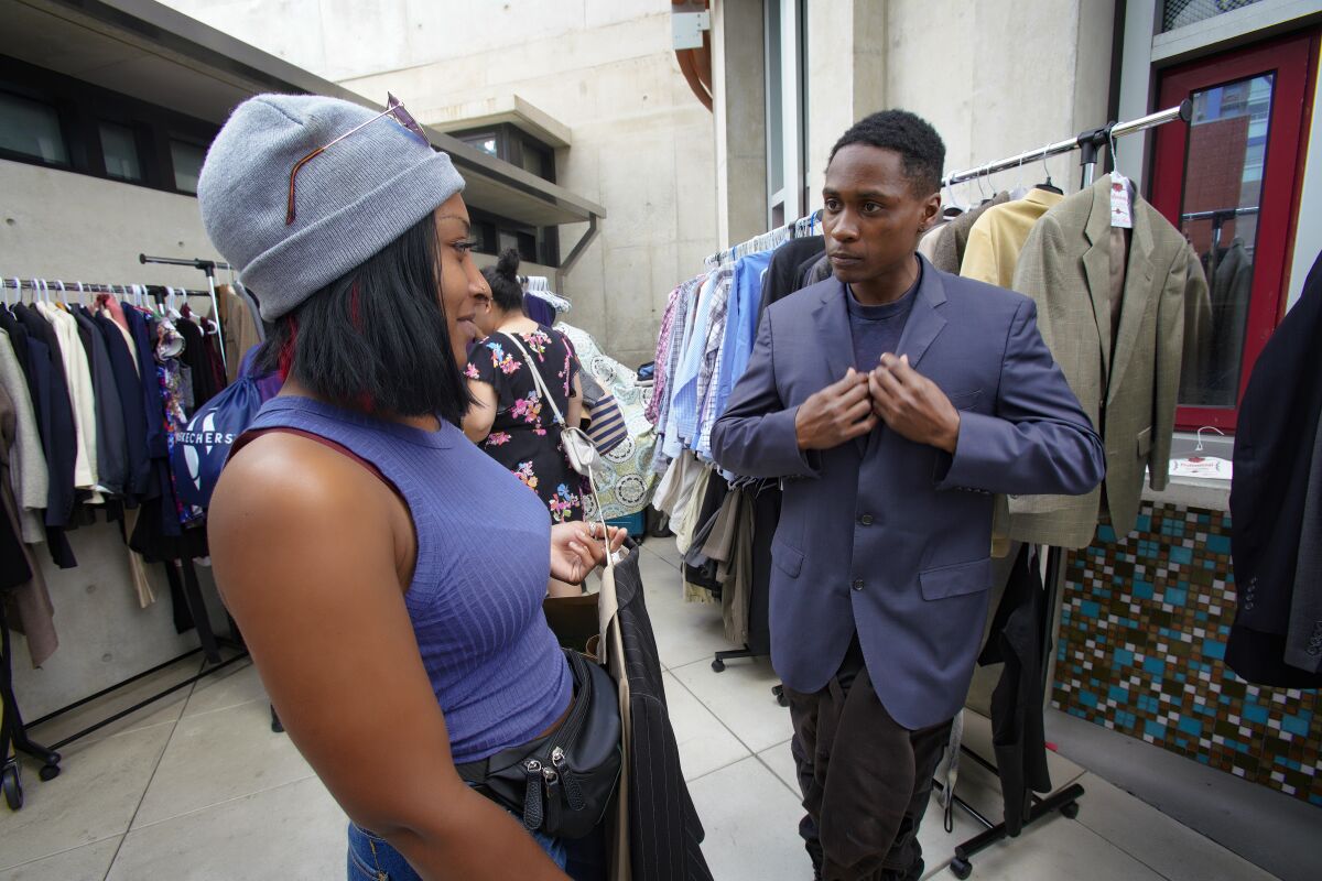 Keenan Gore tries on a suit with his fiancée, Cheyanne Cobb looking on in an event hosted by Think Dignity.

