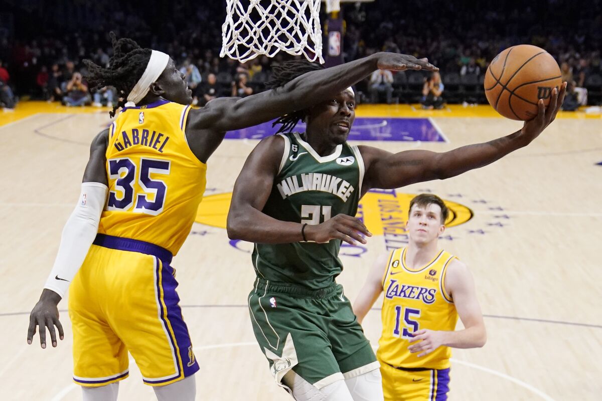 Milwaukee Bucks guard Jrue Holiday shoots as Lakers forward Wenyen Gabriel and guard Austin Reaves defend.