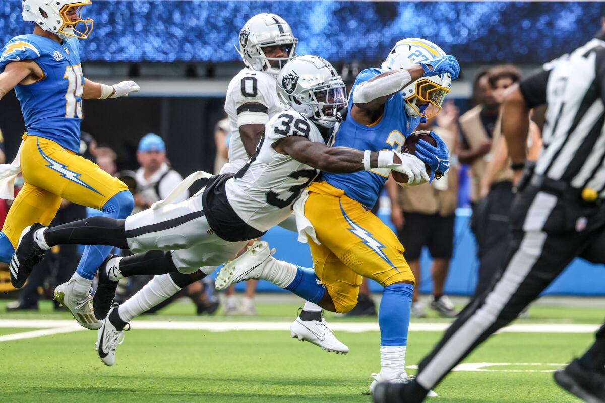 Chargers running back JK Dobbins (27) is tackled by Raiders cornerback Nate Hobbs (39) after a first-down run.