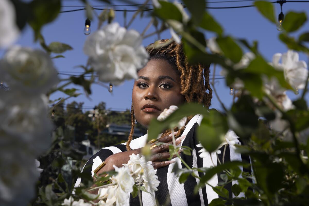 Danielle Brooks peeks through the flowers in a hotel garden for a portrait.