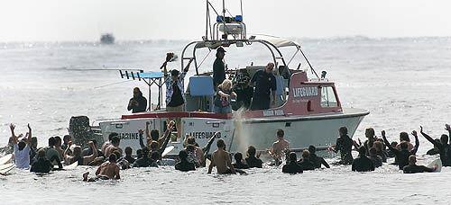 From a San Diego lifeguard boat, Cindy Kauanui spreads the ashes of her slain son as his brother, Nigel, stands at left with arms raised, exulting with hundreds of other surfers who conducted a paddle out ceremony in the surfer's honor.
