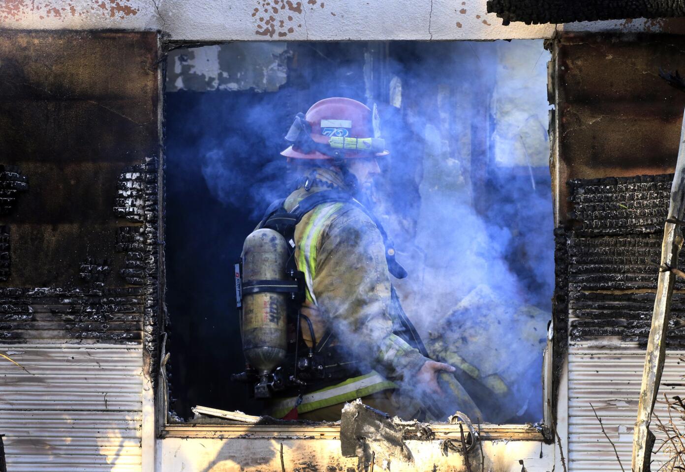 An Orange County Fire Authority firefighter walks through the garage area of a home in Santa Ana destroyed by fire.