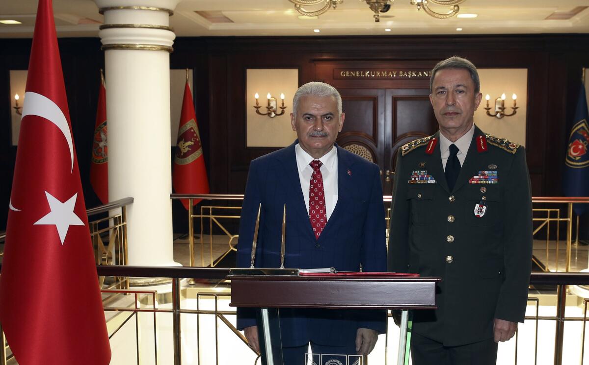 Turkish Prime Minister Binali Yildirim, left, flanked by Chief of Staff Gen. Hulusi Akar, speaks to the press in Ankara on June 2, 2016, about the decision by Germany's parliament to recognize the Armenian genocide.