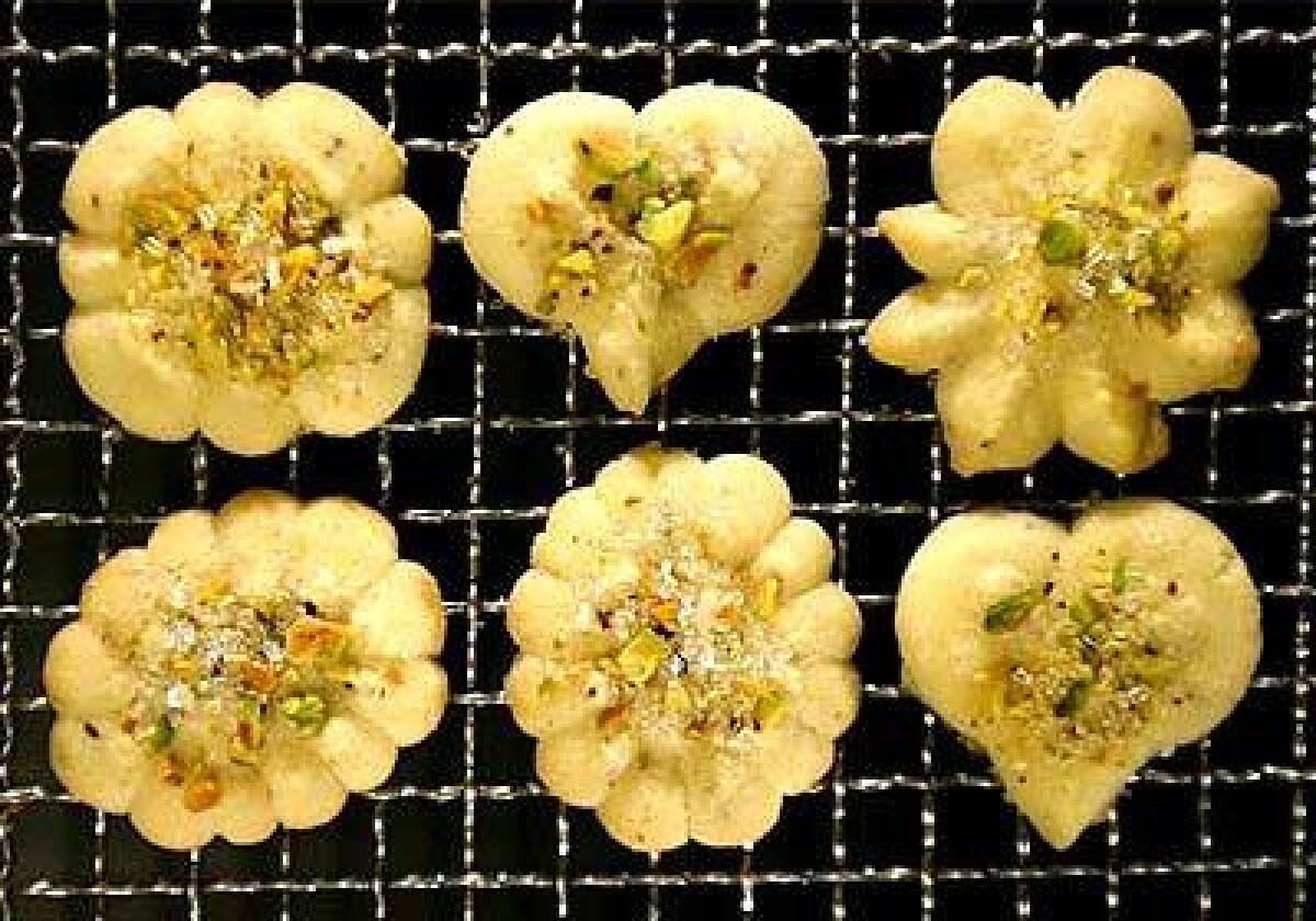 In butter spritz cookies, the cardamom complements the crushed pistachios and the big sugar crystals sprinkled on top. The cookie press, equipped with metal disks of a various shapes, can speed holiday baking by pumping out a dozen cookies in a minute.