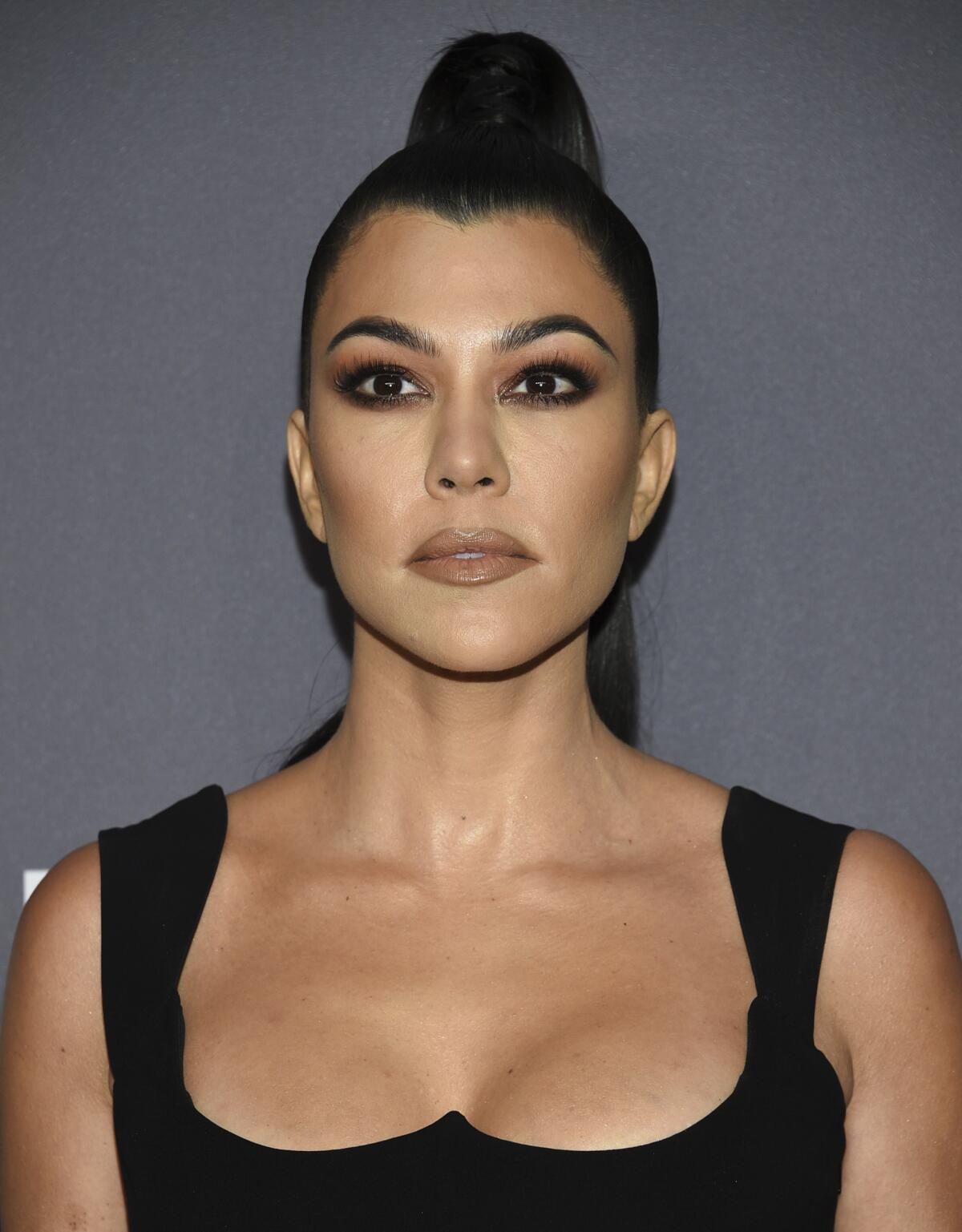 Kourtney Kardashian poses in a tight up-do with a slicked-back ponytail
