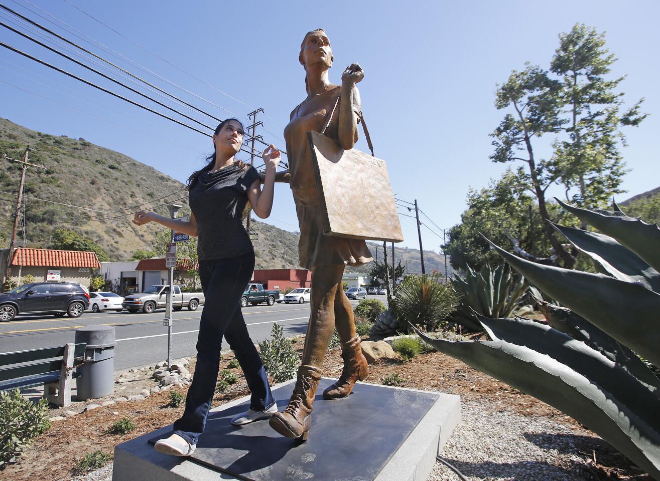 Art model Ifat Glassman reenacts the pose she made for the sculpture "The Art Student" during the Laguna College of Art + Design's unveiling ceremony Thursday for "Canyon Walkers," a trio of sculptures along Laguna Canyon Road in Laguna Beach.