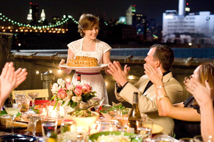 Amy Adams portrays Julie Powell serving a dish to applauding diners in a scene from, "Julie & Julia" (2019)