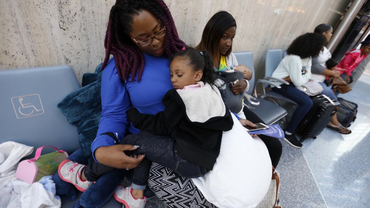 Tiara Daniels holds her niece, De'Shanna Mayes, 5, after they slept all night in the chairs at Southwest Airlines Terminal 1 at LAX. Their 10 p.m. flight home to Denver was canceled; they hope to catch a flight later this morning.