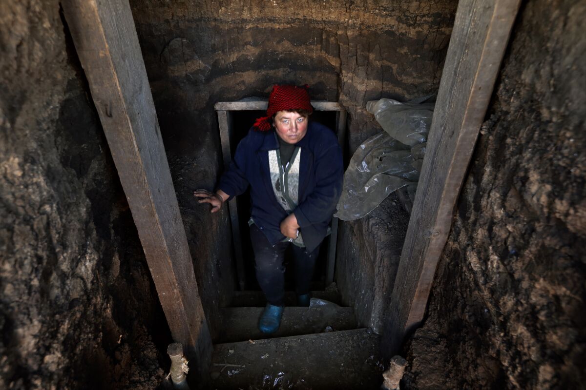 A woman in a red hat and dark clothing stands in a narrow stairwell 