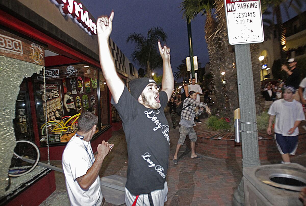 A man appears to celebrate after a stop sign was smashed through the window of a Huntington Beach bike shop.