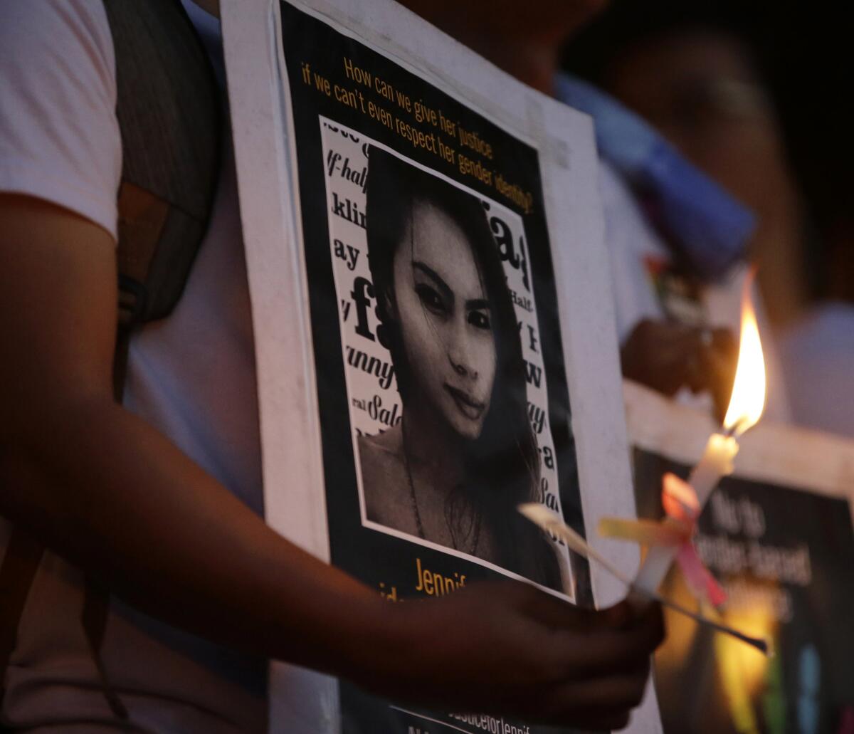 A protester holds a lighted candle in front of a portrait of slaying victim Jennifer Laude during a rally at the University of the Philippines campus in uburban Quezon City on Oct. 24.