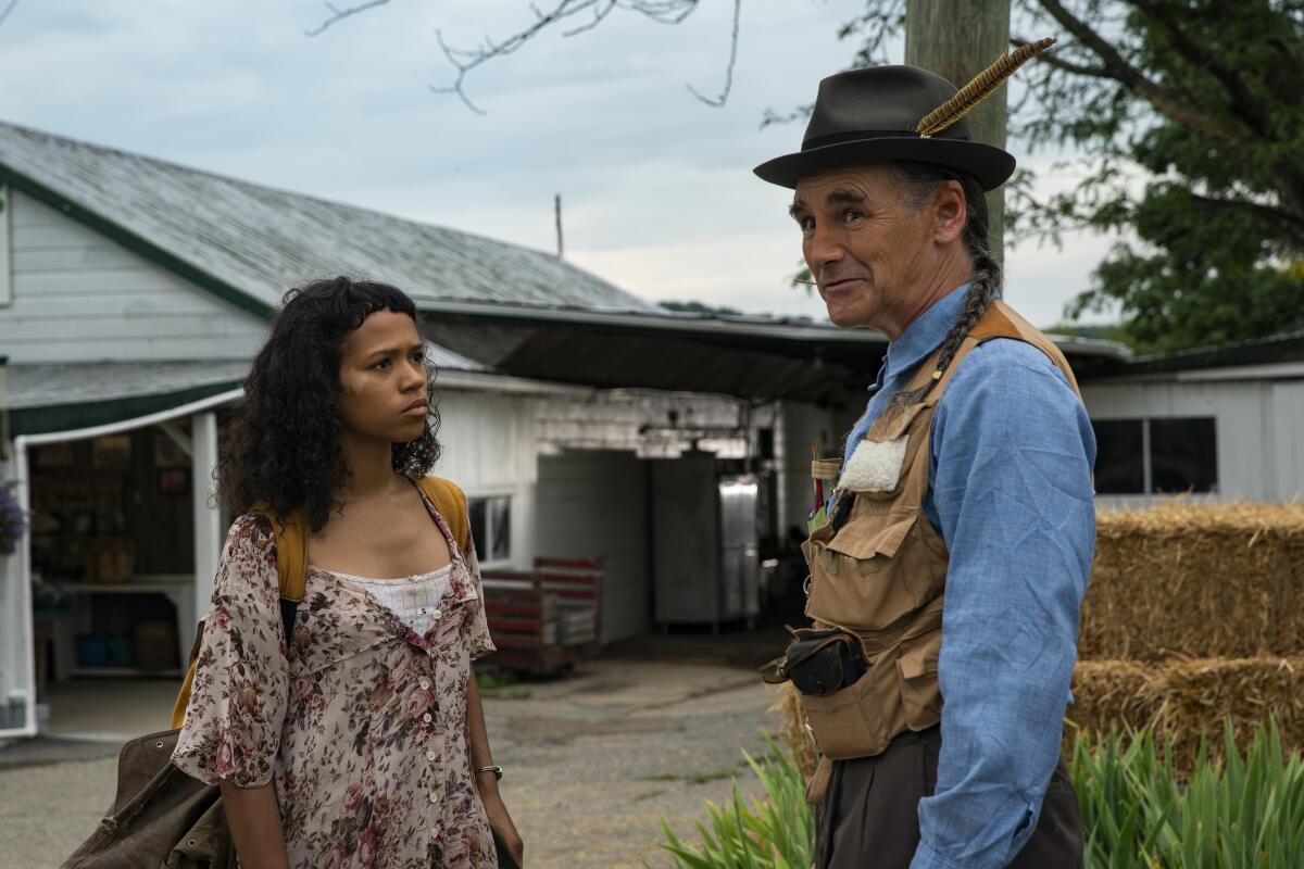 A young woman, left, and an older man outside a weathered house 