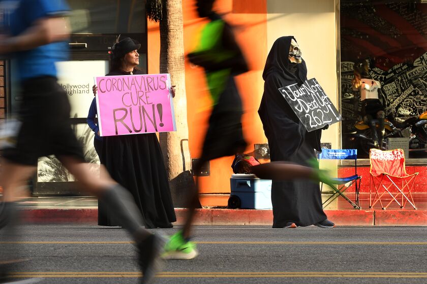 HOLLYWOOD, CALIFORNIA MARCH 8, 2020-Janette Cardona and her husband Louie hold signs along Hollywood Blvd. in Hollywood Sunday as runners compete during L.A. Marathon. (Wally Skalij/Los Angeles Times)