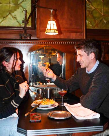 A couple sit in a wood-paneled restaurant booth