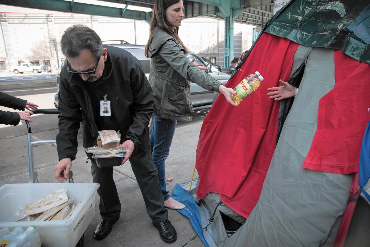 Wayne Garcia and Mary Walker of HealthRIGHT 360 distribute food to homeless people camped under the 101 Freeway in San Francisco.