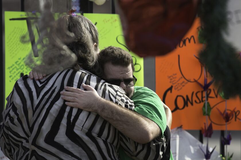 Inland Regional Center client Johnathan Rose, 20, hugs his mother, Marianne Rose, at a makeshift memorial to shooting victims in San Bernardino. The massacre has reopened debate on whether the answer to such shootings is to arm more guards and citizens.