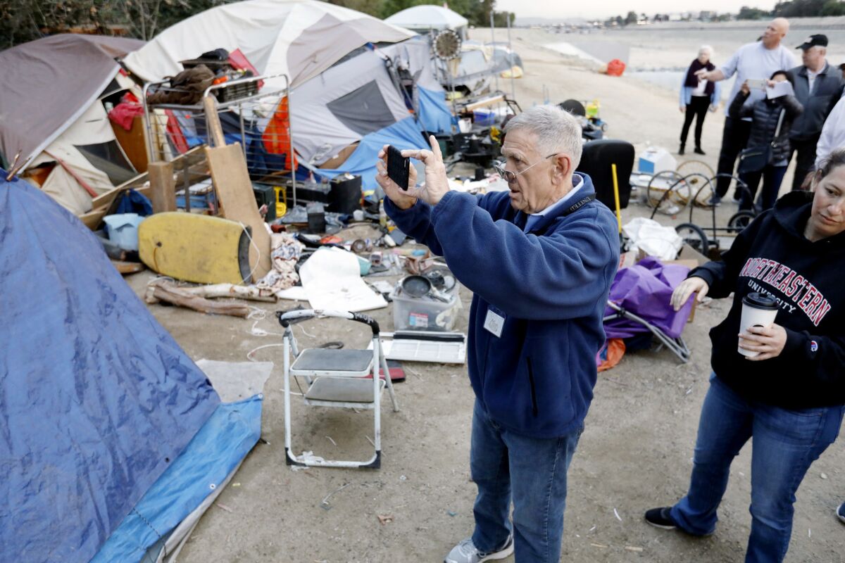 U.S. District Court Judge David O. Carter takes photos at a homeless encampment along the Santa Ana River in Anaheim in 2018.