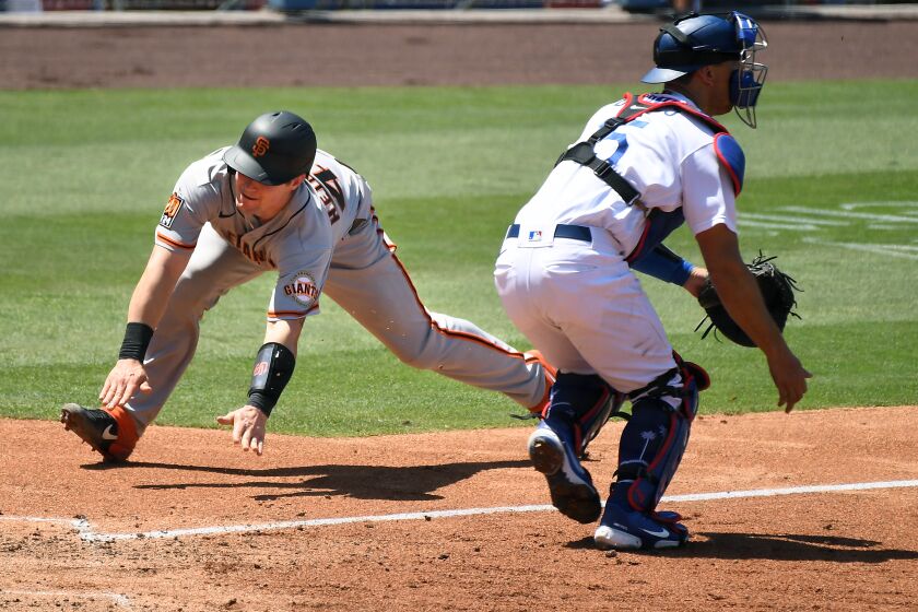 LOS ANGELES, CALIFORNIA JULY 25, 2020-Giants Tyler Heineman scores a run in front of Dodgers catcher Austin Barnes in the 4th inning at Dodger Stadium Saturday. (Wally Skalij/Los Angeles Times)
