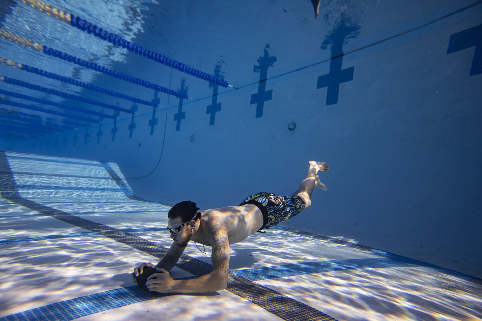 Padres pitcher Joe Musgrove pushes a brick the length of a 13-feet deep competition pool.
