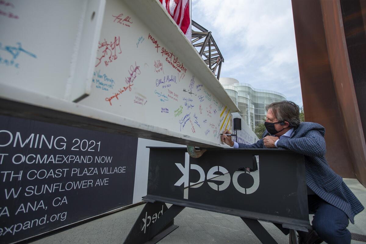 David Emmes, a trustee with The Orange County Museum of Art, signs a beam during a topping out ceremony.