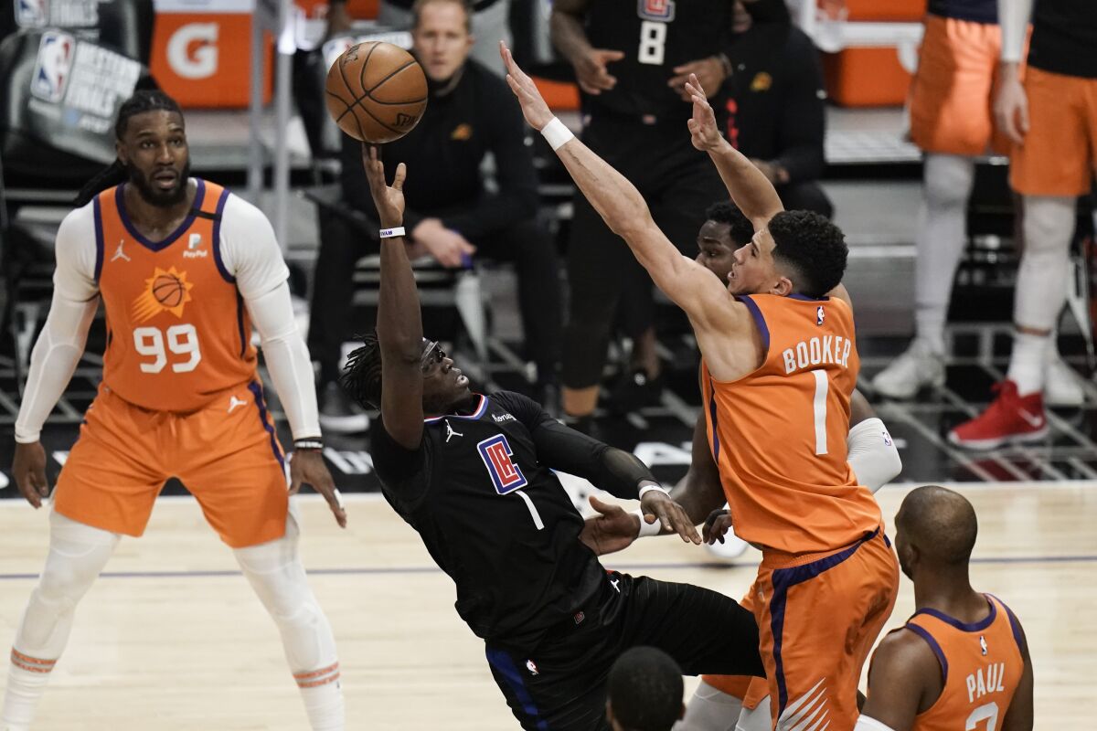 Clippers guard Reggie Jackson, center left, tries to put up a shot over Phoenix Suns guard Devin Booker.
