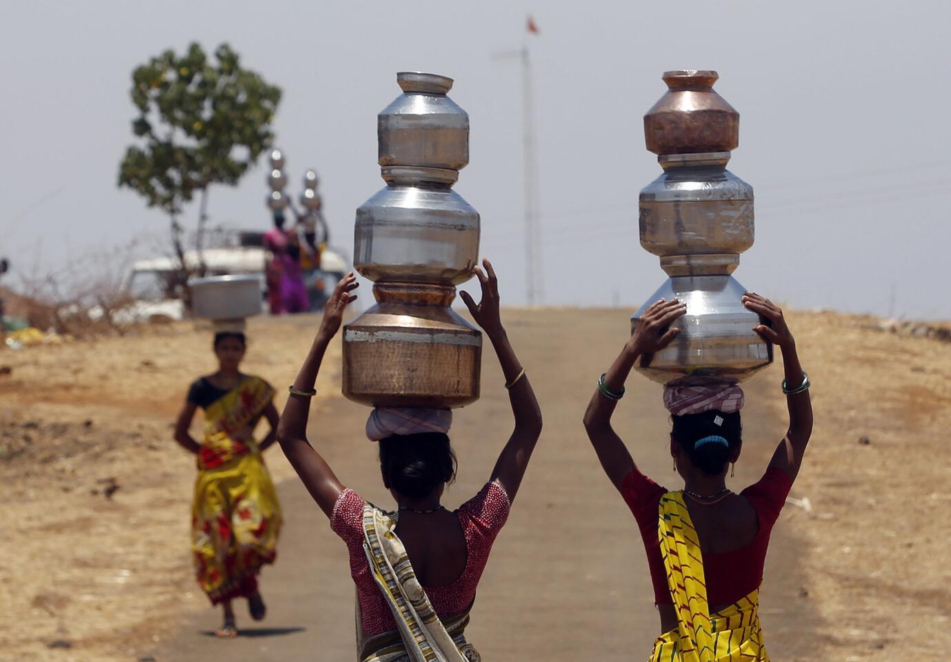 Women walk home after collecting drinking water from a well at Mengal Pada in Maharashtra state, India, on May 4.