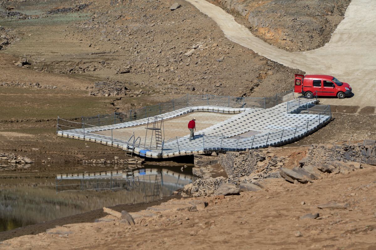 FILE - A man walks on a floating swimming pool resting on dry ground of the water depleted Zezere River due to drought near, Pampilhosa da Serra in central Portugal, Thursday, Feb. 17, 2022. Almost the whole of Portugal was in severe drought at the end of May, the country’s weather service said Thursday, June 9, 2022. The month of May was the hottest in the southern European country for the last 92 years, weather service IPMA said in its monthly climate report. (AP Photo/Sergio Azenha, File)