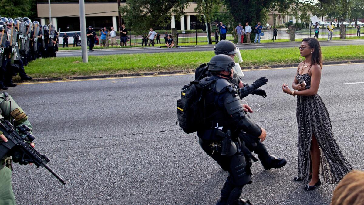 A protester is grabbed by police officers in riot gear after she refused to leave the street in front of Baton Rouge, La., police headquarters July 9.