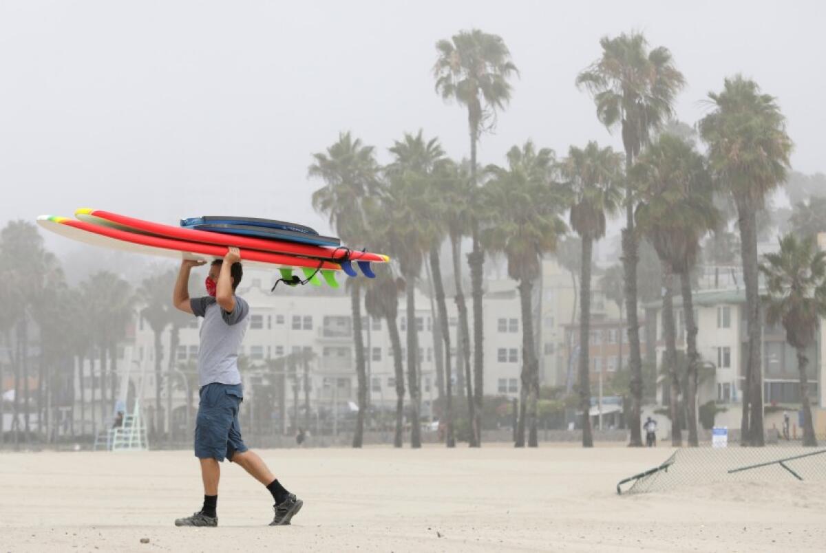 Peter Gratzinger of Pacific Palisades carries boogie boards and surfboards at Santa Monica State Beach. 