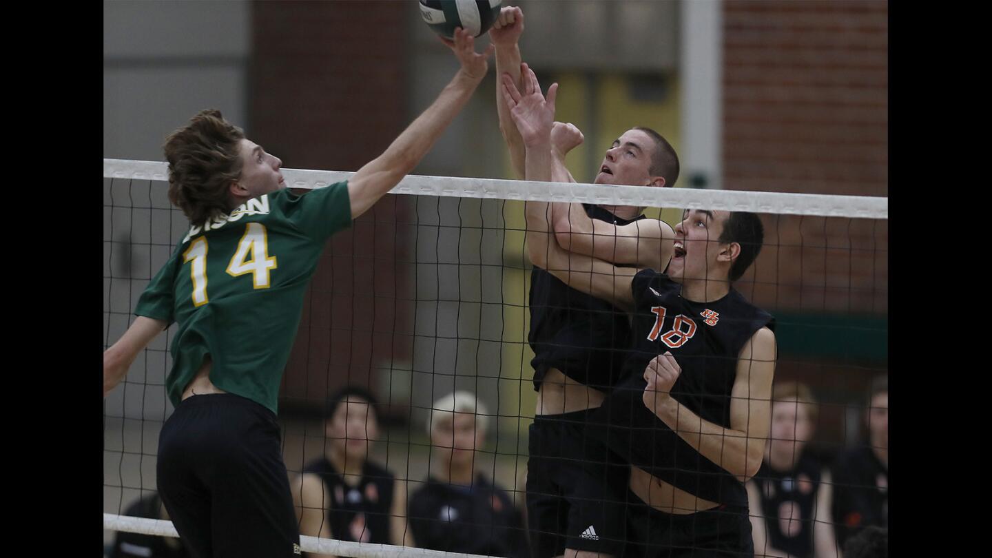 Huntington Beach High's Nathan Goode, center, and Drake Goering (18) battle at the net against Edison's Justin Pennington (14) during the second set of a Sunset Conference crossover match at Edison on Wednesday.