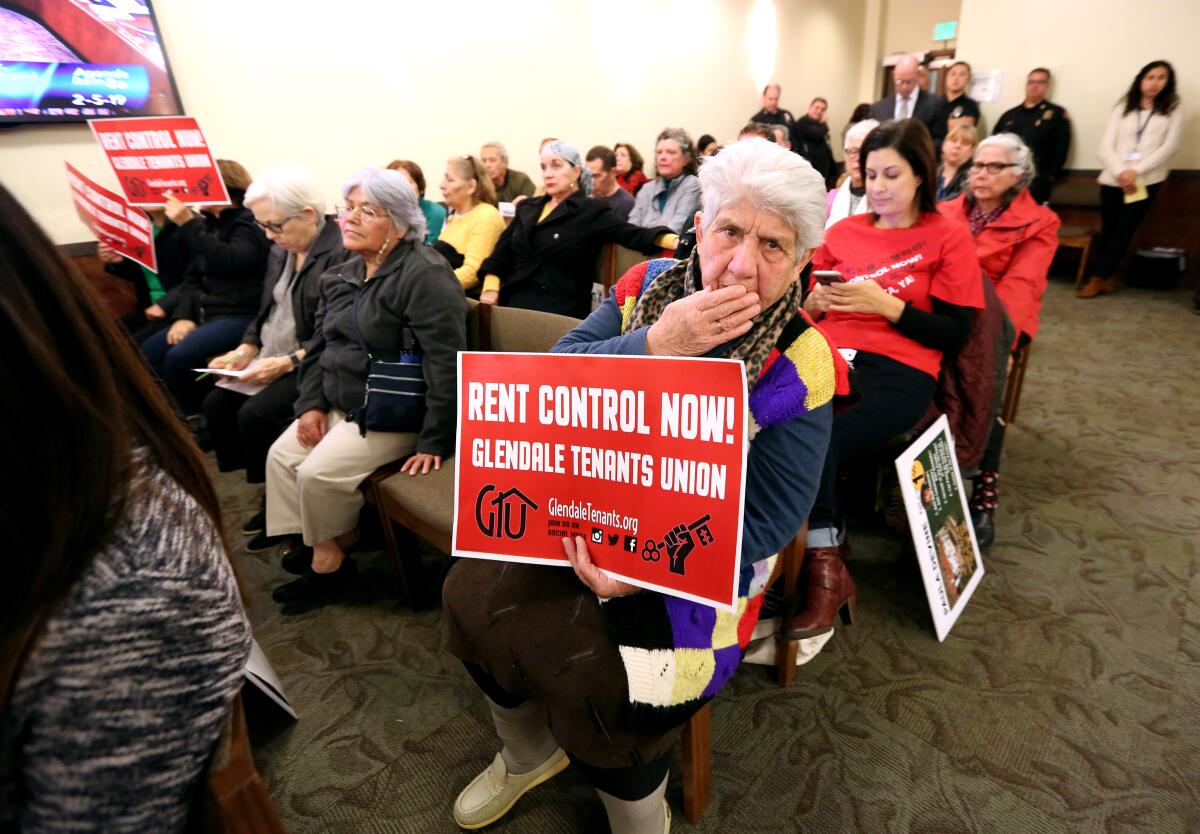 A woman holds a Glendale Tenants Union sign calling for local rent control during a council meeting at Glendale City Hall in early February 2019. About a week later, the city would adopt an ordinance that fell short of rent control but affords tenants additional protections, including relocation fees under certain circumstances.