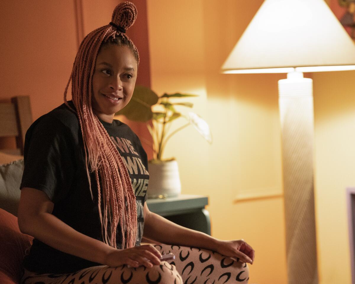 A woman sits on her bed looking skeptical.