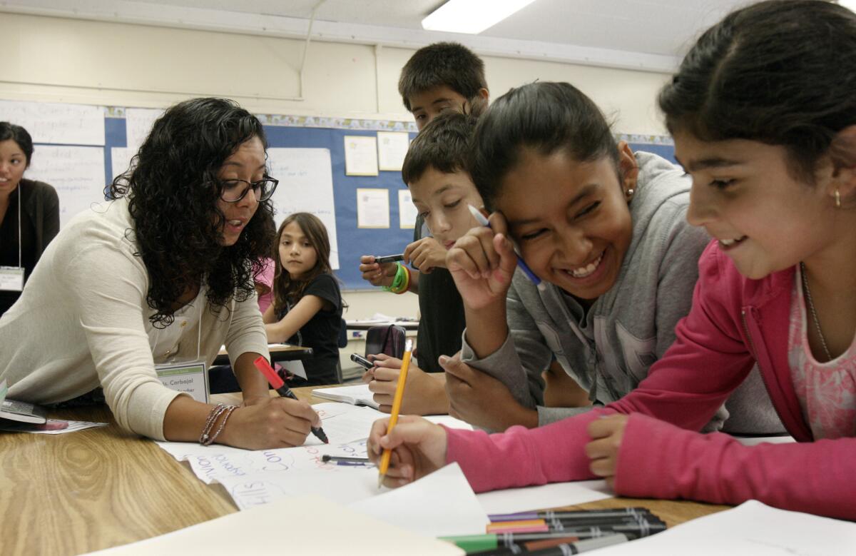 A new law will extend the length of graduate teacher training programs to two years. Here, Angie Carbajal, left, a trainee in the Urban Teacher Residency preparation program, instructs students at Gage Middle School in Huntington Park.