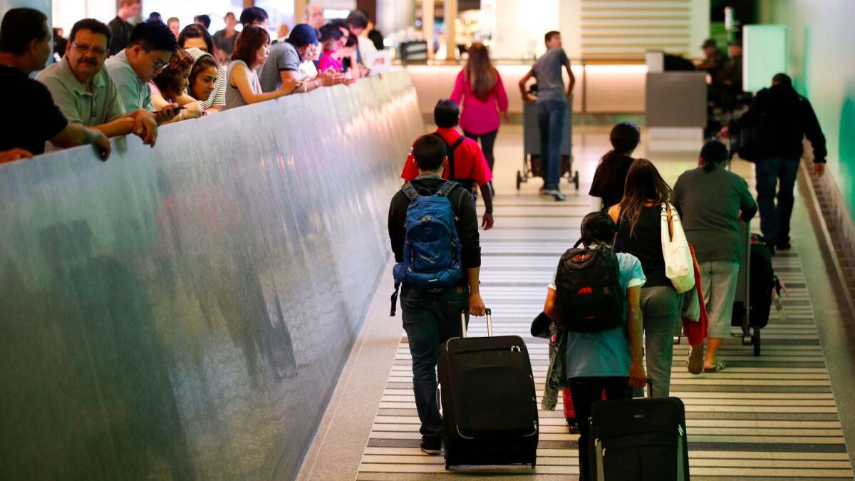Travelers make their way up the arrival ramp at the Tom Bradley International Terminal at Los Angeles International Airport on Thursday. (Jae C. Hong / AP)