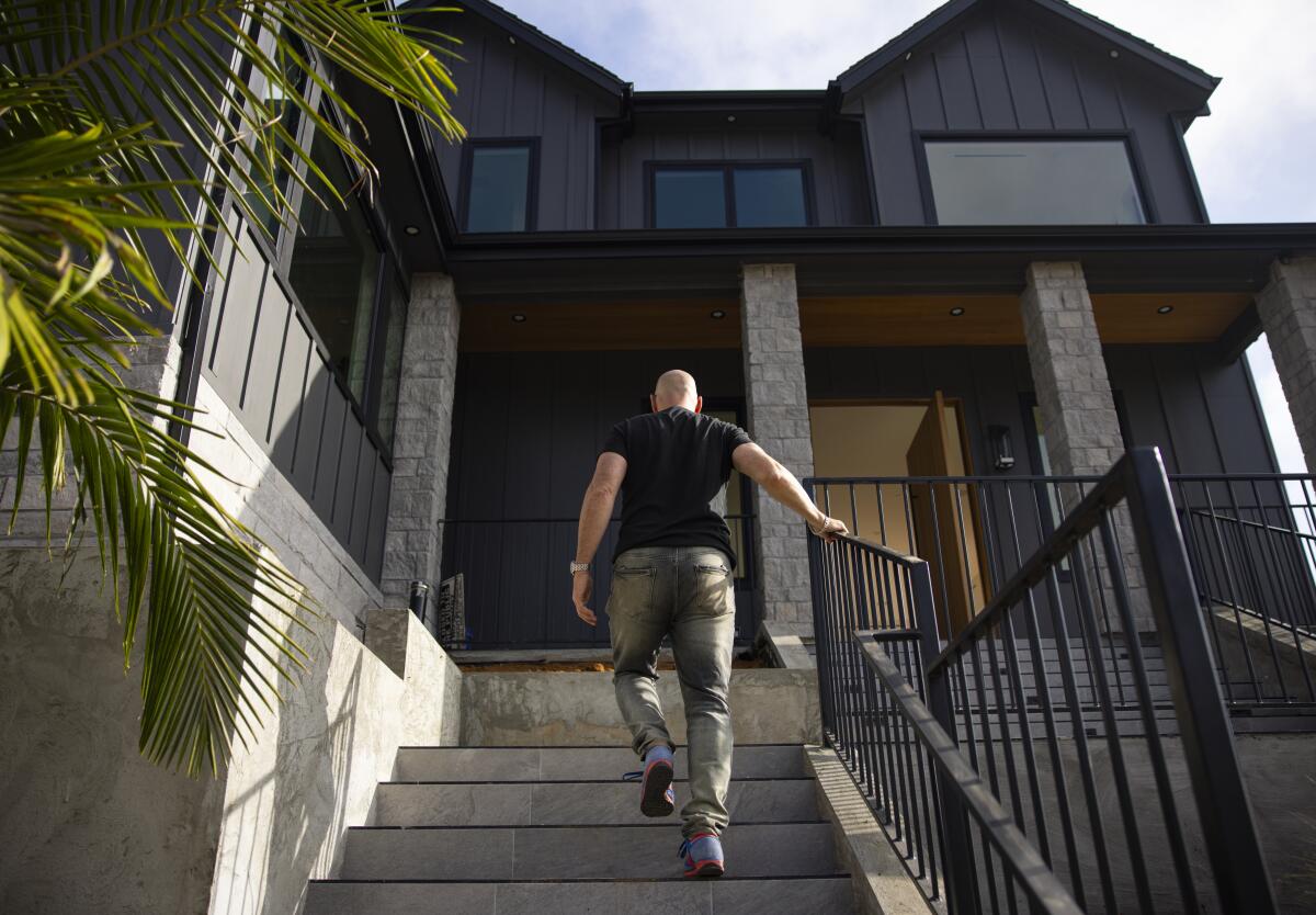 Craig Forrest holds a handrail as he walks up the steps of his newly rebuilt home