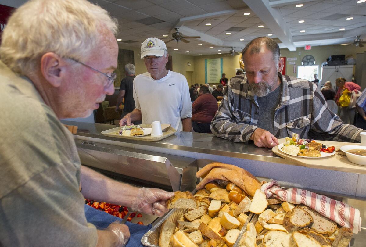 Al Nieman, left, from Portland, Ore., serves food to Dennis Sundman, center, and Shannon Carder at the Someone Cares Soup Kitchen in Costa Mesa on Friday. The facility won $10,000 worth of merchandise from IKEA to help with a planned makeover.