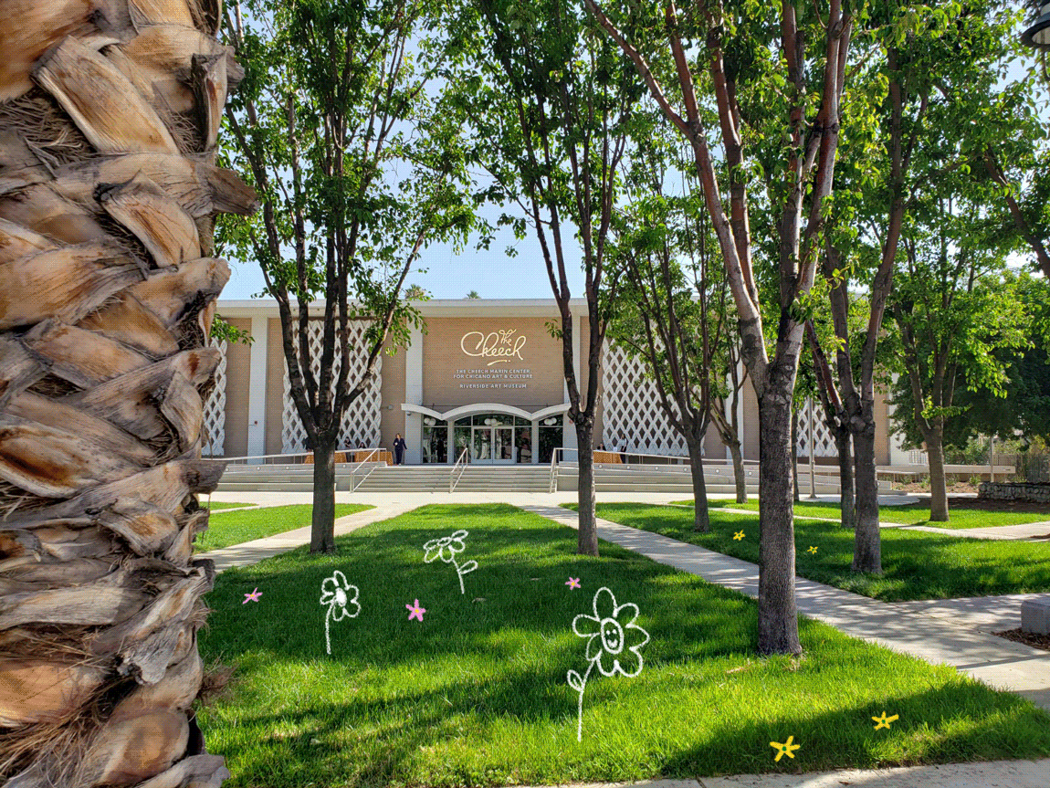 The entrance to a large building is seen through a grove of trees.