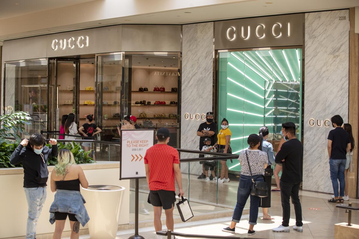 Shoppers wait in line outside Gucci last week as South Coast Plaza in Costa Mesa reopens.