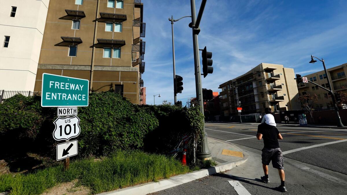 People walk by apartments built along the 101 Freeway in the Boyle Heights neighborhood of Los Angeles.