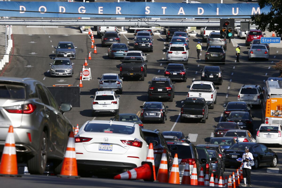 A busy line of cars and multiple orange traffic cones in front of the entrance to Dodger Stadium