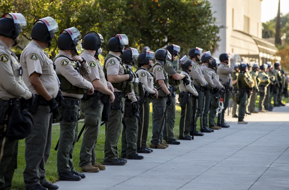 Riverside County deputies stand in a line in riot gear