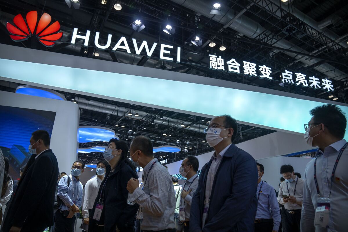 ARCHIVO - Los visitantes pasan por delante de un stand de la empresa tecnológica china Huawei en la PT Expo de Beijing el 28 de septiembre de 2021. (AP Foto/Mark Schiefelbein, Archivo)