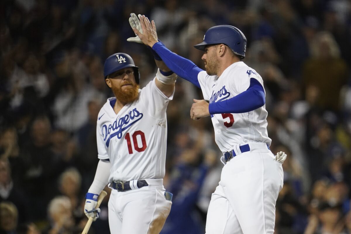 Los Angeles Dodgers designated hitter Justin Turner (10) high-fives Freddie Freeman (5) after Freeman scored off of a single hit by Trea Turner during the eighth inning of a baseball game against the Cincinnati Reds in Los Angeles, Thursday, April 14, 2022. (AP Photo/Ashley Landis)