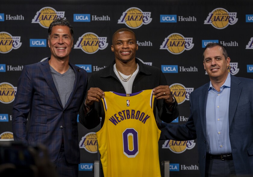 Russell Westbrook holds up his Lakers jersey while flanked by Rob Pelinka. left, and Frank Vogel, right. 